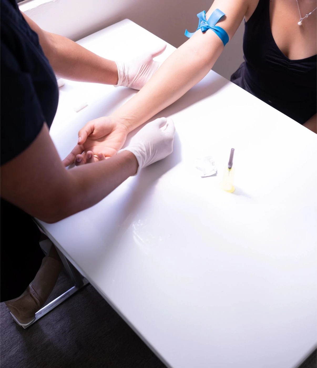 Clinician in gloves preparing to take a blood sample from a patient’s arm